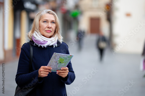 mature woman tourist with a map in hand walks the streets of the town