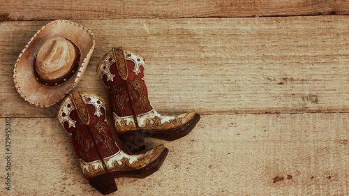 cowboy boots and hat on a wood background with vintage effect and writing space