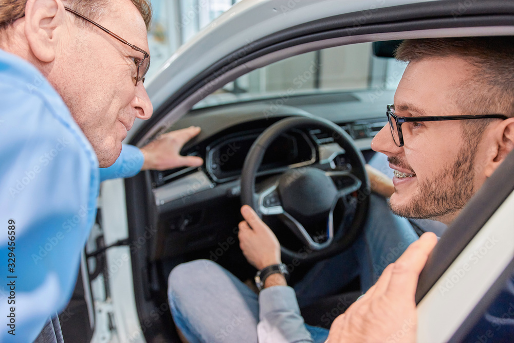 Test drive. Sales manager showing customers interior of a new car model