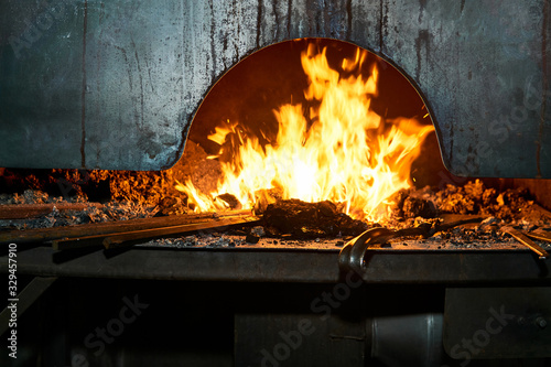 Photo blacksmith furnace with burning fire with billets heating on it