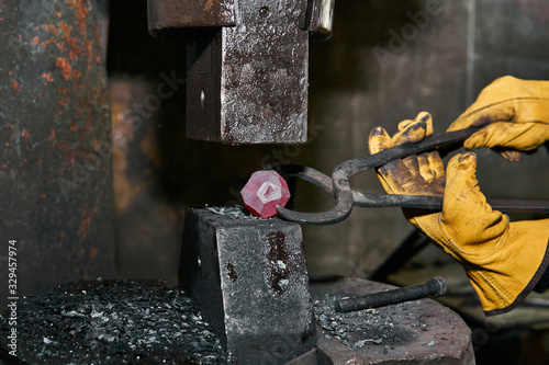 machine hammer turns into a sphere a metal workpiece held by a blacksmith with pincers photo