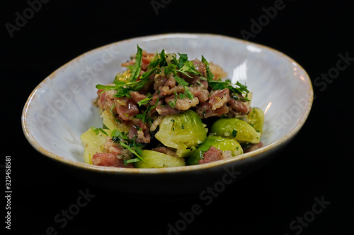 cooked Brussels sprout with beef bacon in a serving bowl with black background