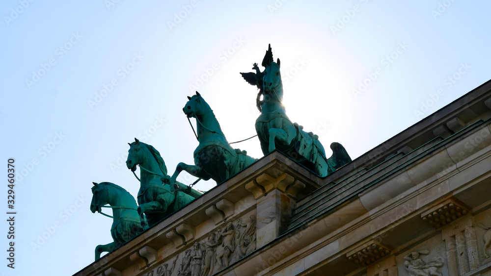 Brandenburg Gate against the sun. Close up. Major landmark and national symbol of Berlin, Germany. Statue of the Goddess Victoria with Horses on Brandenburg Tor. Viewed from the Pariser Platz. 