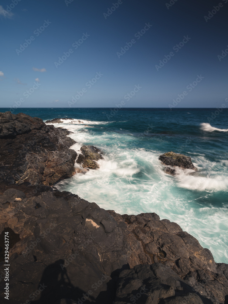 waves crashing on rocks near coastline of island in Kauai, Hawaii waves crashing on rocks near coastline of island in Kauai, Hawaii