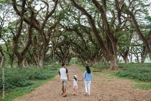 Asian families enjoy holidays together, father, mother and two children walking in the park