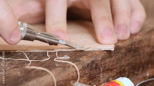 Beveling the edges of a piece of vegetable tanned leather closeup using an edge beveler photo