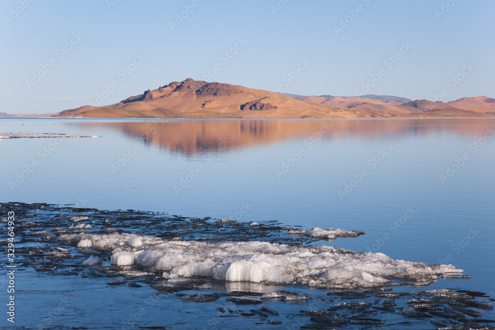 lake in mongolia with snow and hills at background