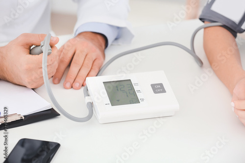 Male doctor measuring blood pressure of female patient in hospital
