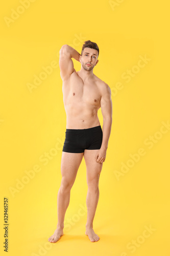 Handsome man in underwear on color background