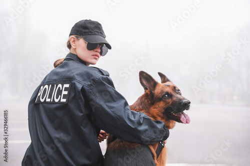 Female police officer with dog patrolling city street
