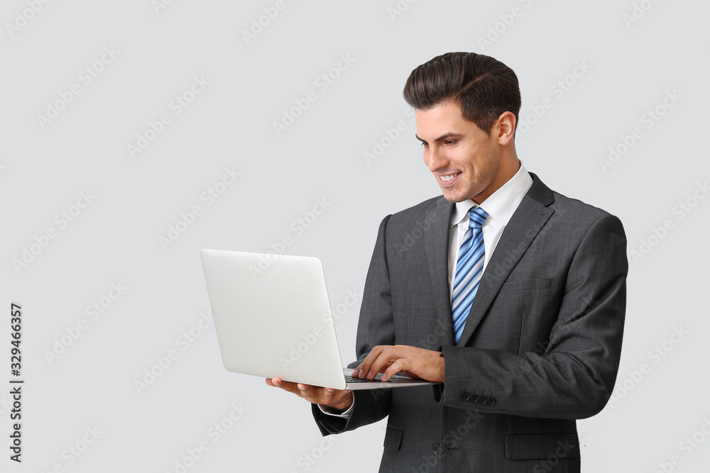 Handsome businessman with laptop on light background Handsome businessman with laptop on light background