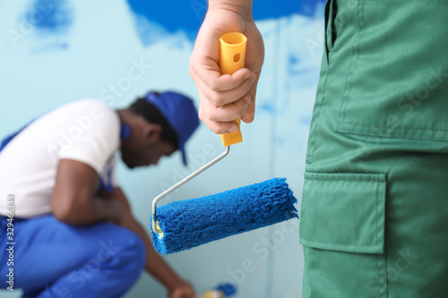 Male painters doing repair in room, closeup photo