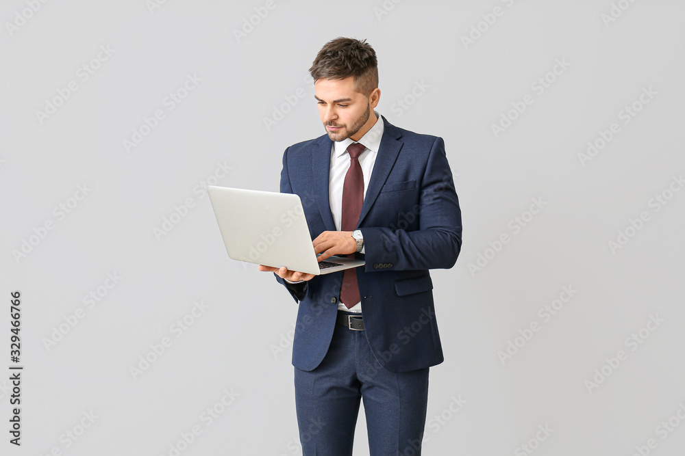Handsome businessman with laptop on light background Handsome businessman with laptop on light background