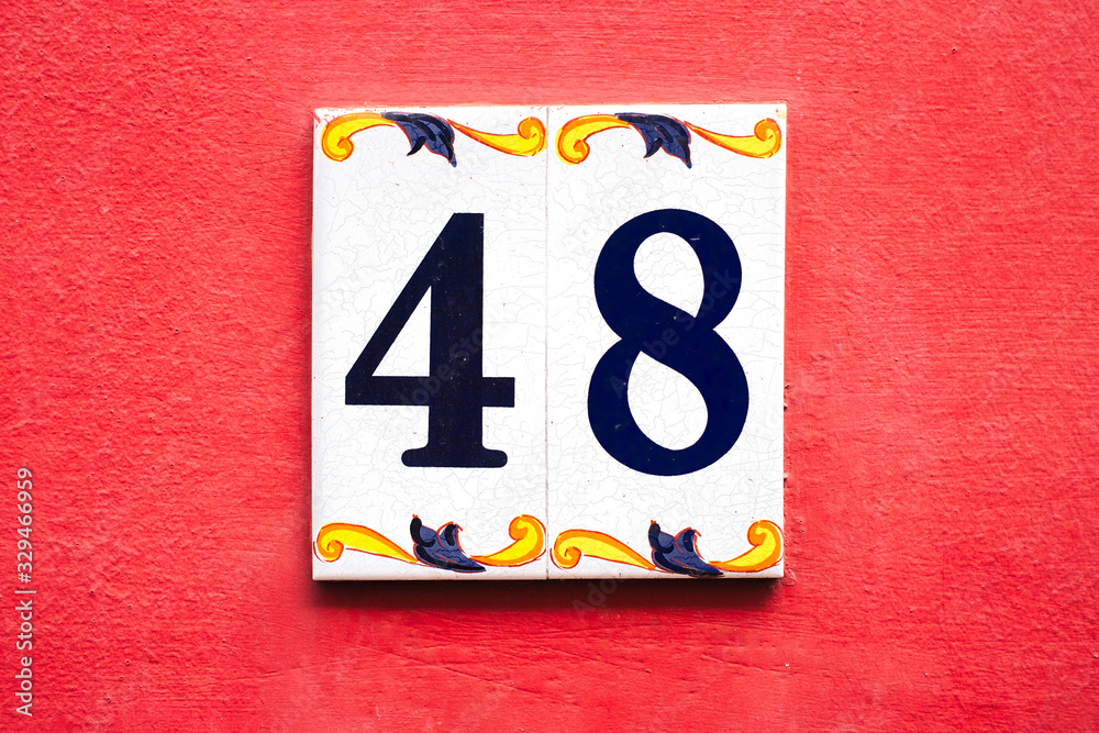 Number 48, forty-eight, decorative tiles on a red wall. Number 48, forty-eight, decorative tiles on a red wall.