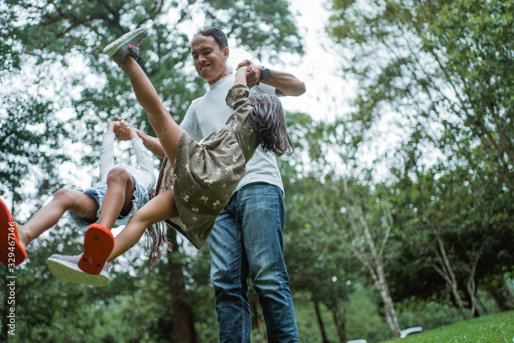 asian father lift up two daughter to swing with arms when playing in the park asian father lift up two daughter to swing with arms when playing in the park