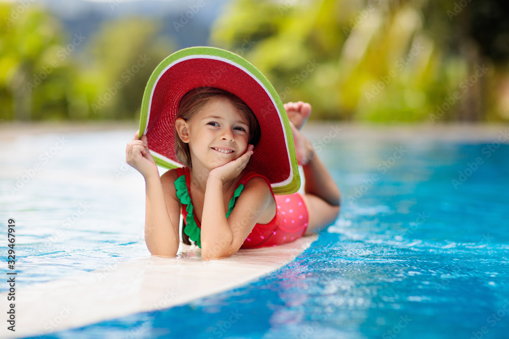Child with hat in swimming pool. Tropical vacation
