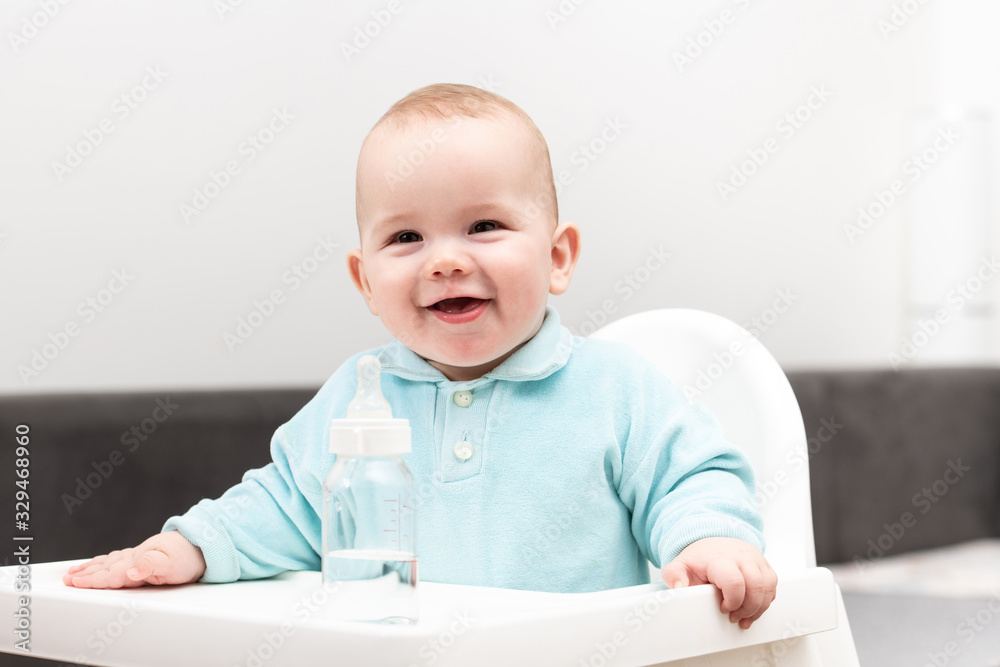 Portrait Of Baby Child With Bottle In Chair
