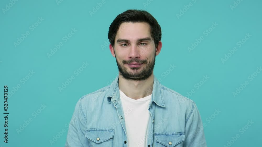 Comical stupid bearded guy in jeans shirt looking cross-eyed and making funny awkward silly grimace, playing fool, pretending to be dumb, brainless. indoor studio shot isolated on blue background Comical stupid bearded guy in jeans shirt looking cross-eyed and making funny awkward silly grimace, playing fool, pretending to be dumb, brainless. indoor studio shot isolated on blue background