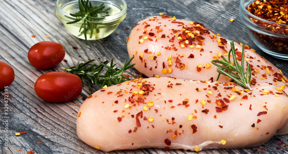 raw chicken breast with rosemary, vegetables and red pepper on wooden board raw chicken breast with rosemary, vegetables and red pepper on wooden board