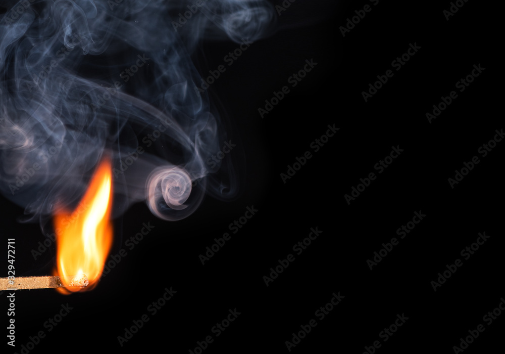 Match bursting into flame with smoke against black background Match bursting into flame with smoke against black background