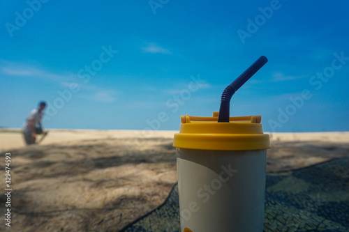 Stainless steel coffee mug on the sand behind the sea