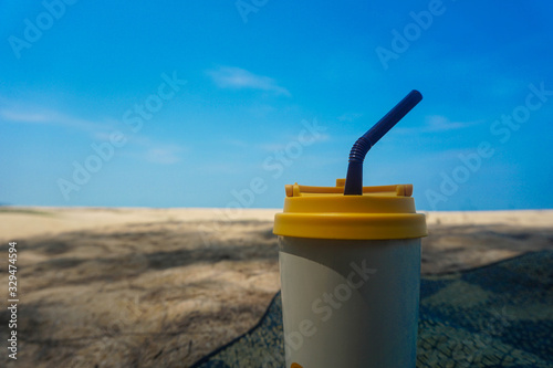 Stainless steel coffee mug on the sand behind the sea