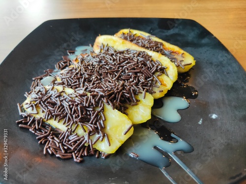 Fried Banana with Chocolate Ceres on Black Plate. Selective Focus photo