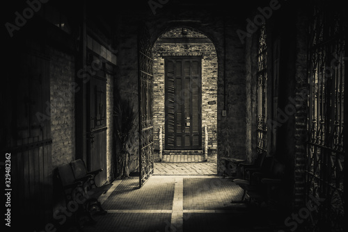 Tablou canvas Drawing-like view of scary passage leading to an old brick arch with a rusty open iron gate, heading to a broken blind