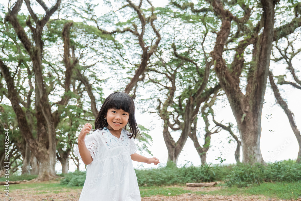 little girl running around the forrest wearing white dress little girl running around the forrest wearing white dress