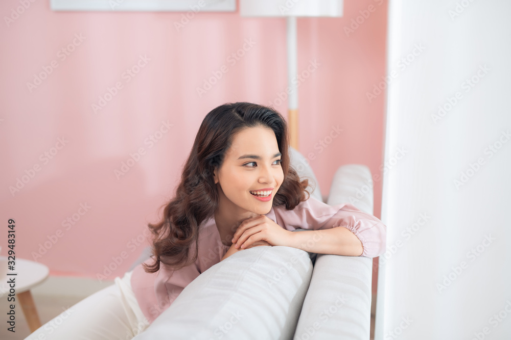 Young Asian woman sitting on couch and relaxing. Young Asian woman sitting on couch and relaxing.