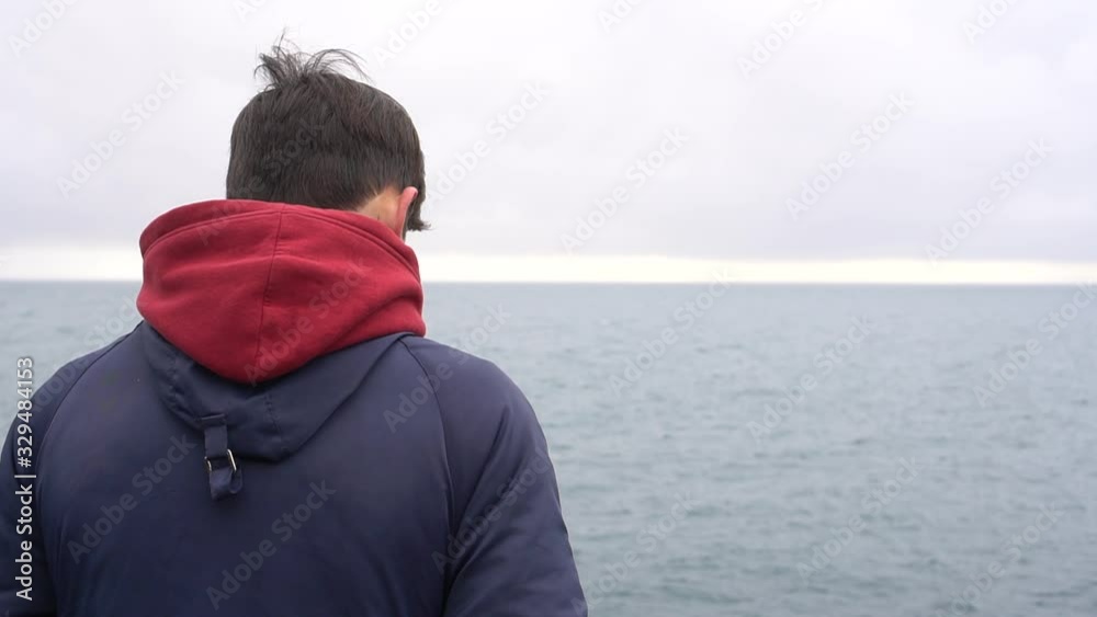 Alone Teenager In The Evening Looking at the Sea and Evening Sky. Outdoors. Silhouette at the sunset sky background Alone Teenager In The Evening Looking at the Sea and Evening Sky. Outdoors. Silhouette at the sunset sky background