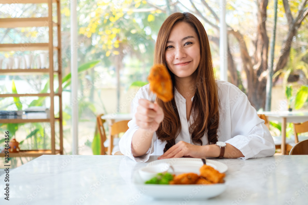 Closeup image of a beautiful asian woman showing and eating fried chicken in restaurant Closeup image of a beautiful asian woman showing and eating fried chicken in restaurant