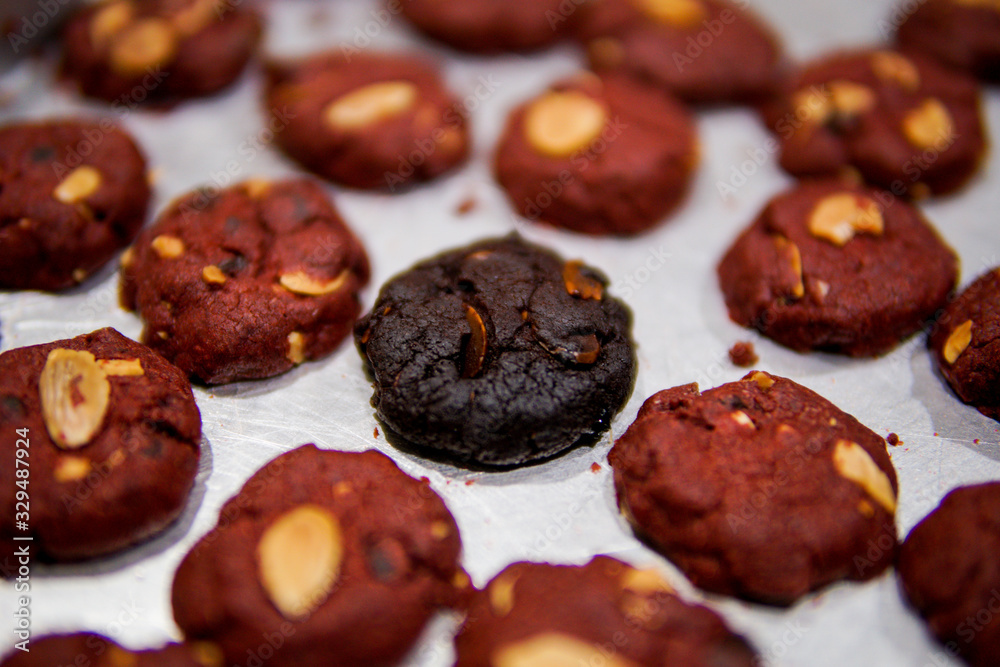 Burnt cookies in the middle of red velvet cookies on a tray