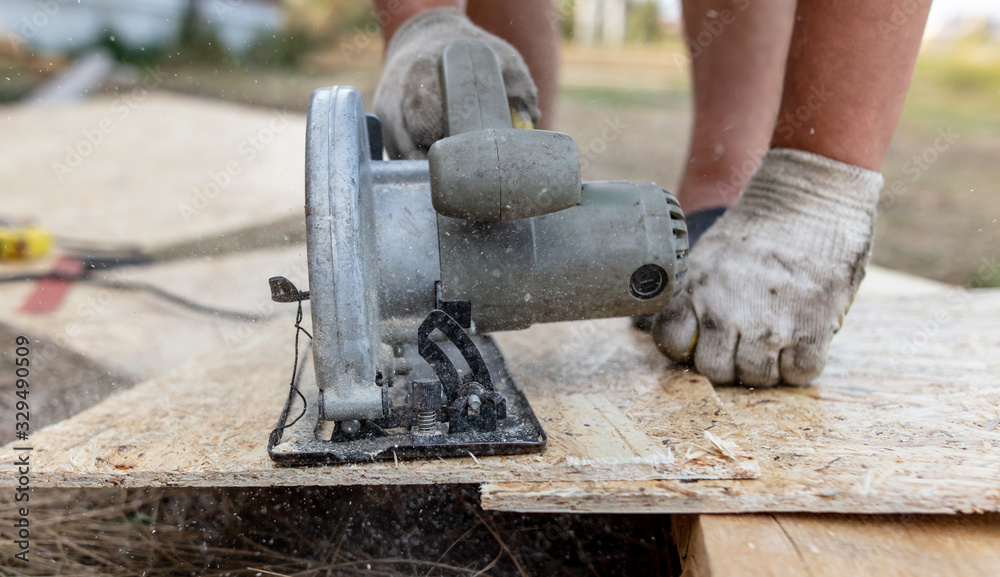A worker saws a wooden beam. A worker saws a wooden beam.