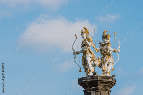 The statue of Nakula & Sadewa stands tall at a height of blue sky.