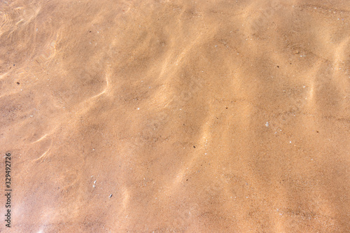 Ripples of water waves reflecting texture on a sandy beach bottom