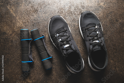 Fitness concept. Black sports shoes and dumbbells.
