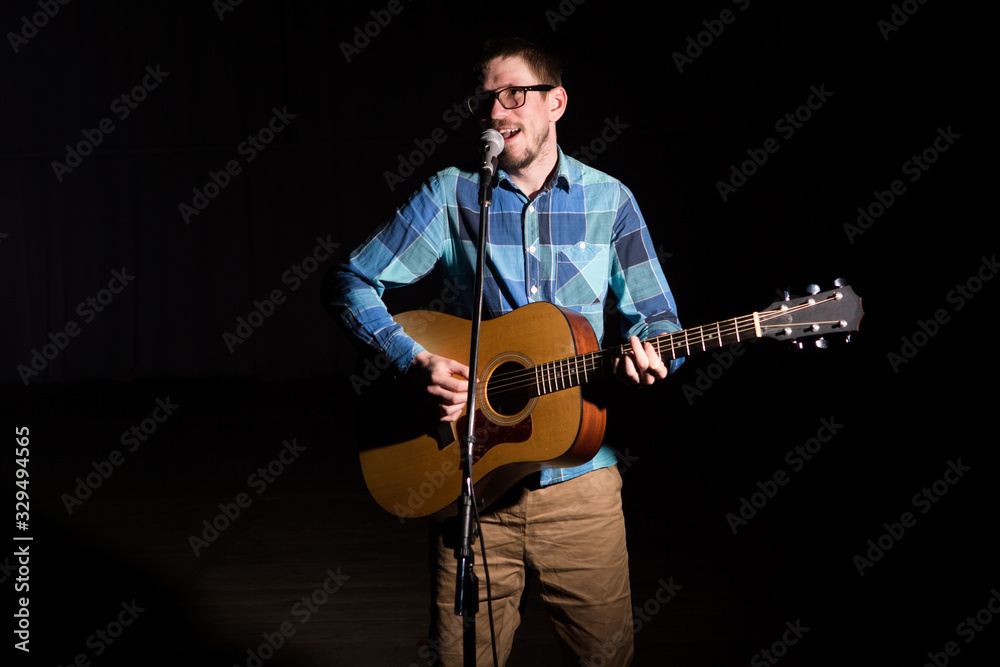 Obraz premium Musician in a plaid shirt plays on an guitar. Low key portrait