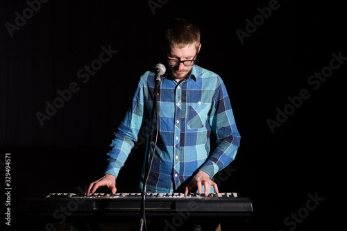 Musician man play keyboard on dark background