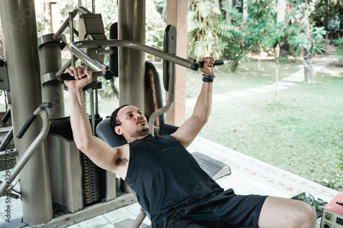 Asian young man doing chest press exercise at firness house photo