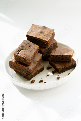 Chocolate brownie sliced into square slices on a white plate.