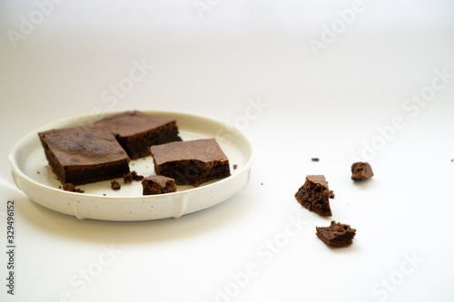 Chocolate brownie sliced into square slices on a white plate.