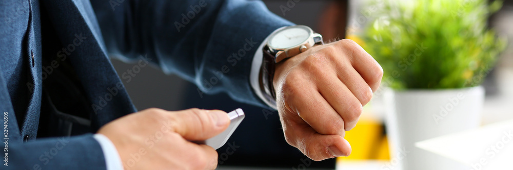 Man in suit and tie check out time at silver wristwatch closeup. Show and point with finger waste minute modern punctual life style start hurry job idea last second clockwork precision concept