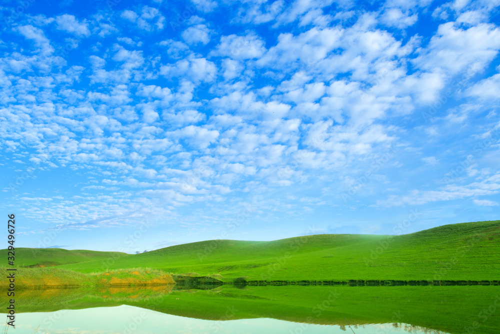 Morning on the lake with green hills and reflection
