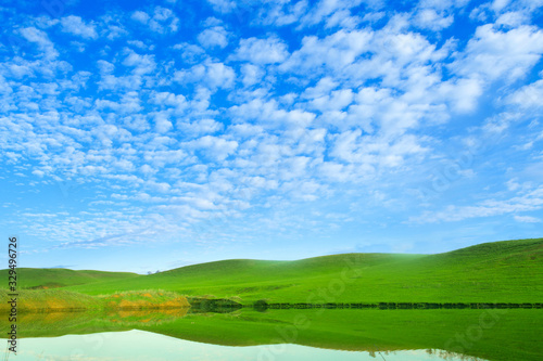 Morning on the lake with green hills and reflection