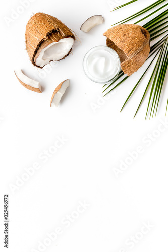 Skin care cream with coconut oil on white background top-down frame copy space