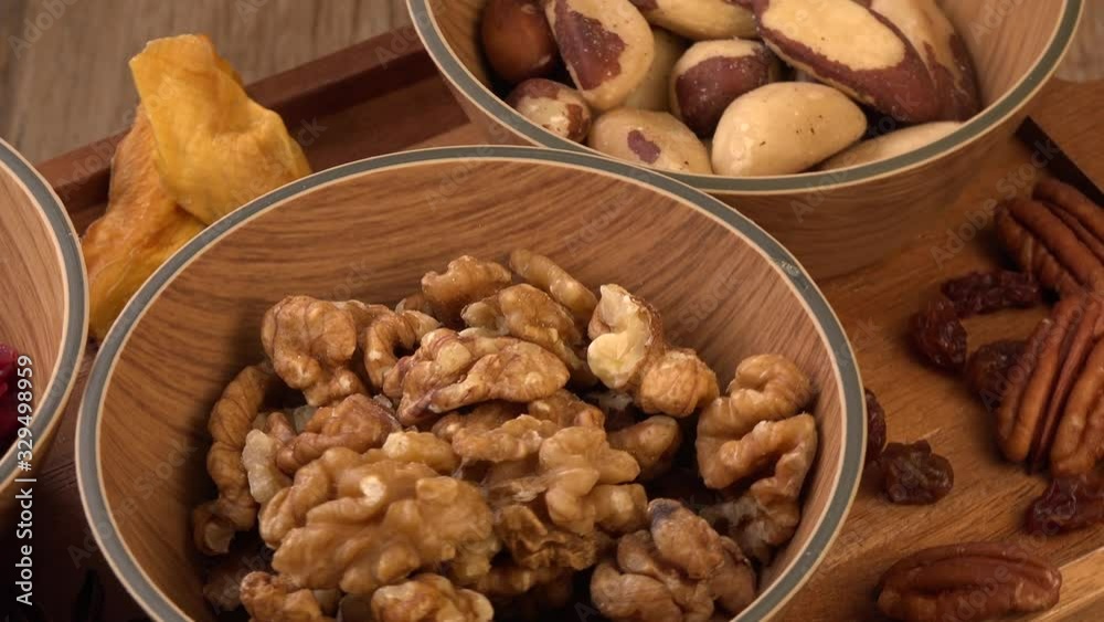 Mixed nuts and dried fruits in wooden bowl on wood background, copy space