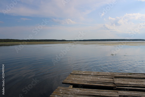 Waves on a lake covered with green grass under a blue sky with clouds