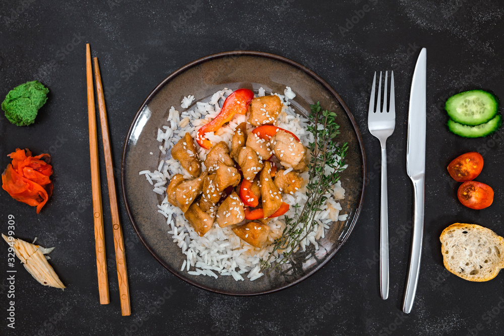 Tasty chicken with rice on brown plate on black background. Asian vs European cuisines. friendship and comparison. Tasty chicken with rice on brown plate on black background. Asian vs European cuisines. friendship and comparison.