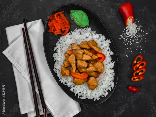 Rice with chicken and vegetables on black background. Chinese dish. Horizontal shot.